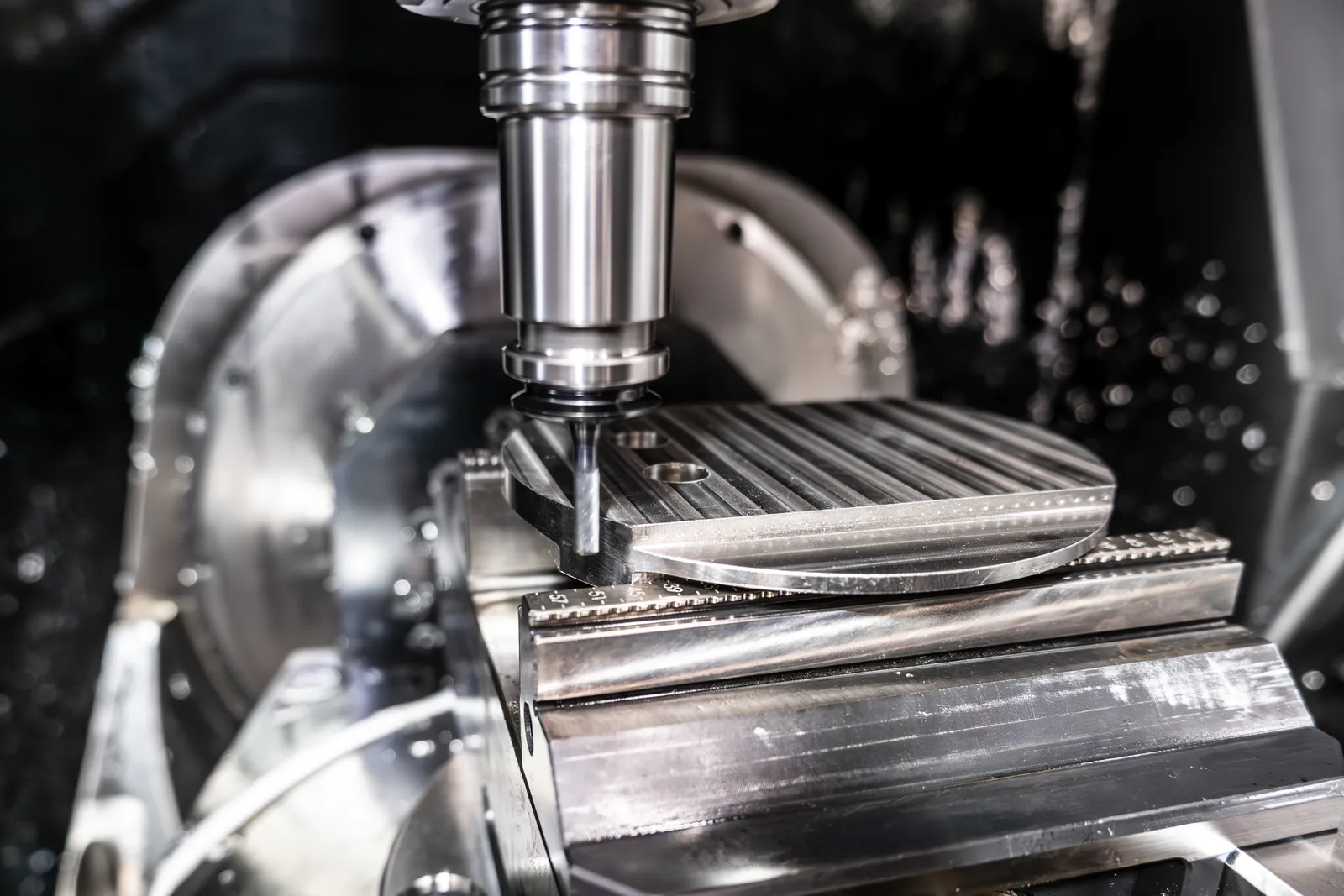 A five-axis spindle cutting a metal part under coolant on an Ethereal Machines CNC